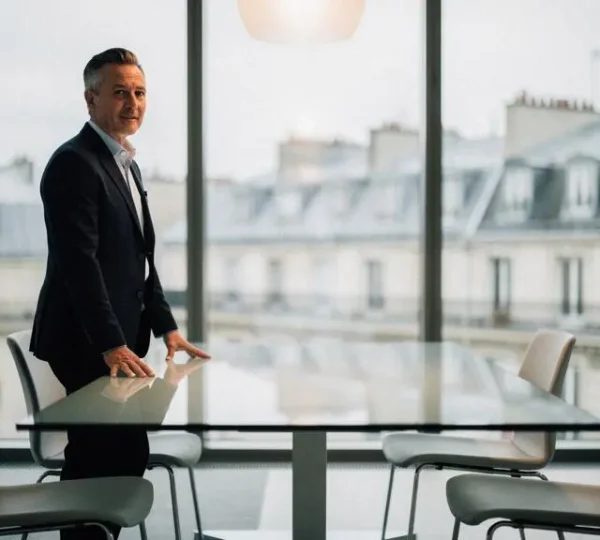 Dirigeant d'entreprise en reflexion dans une salle de reunion moderne, symbolisant l'equilibre entre actionnaires, salaries, clients et investisseurs